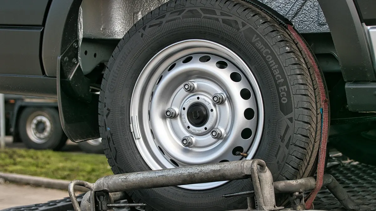 Roda de carro fixada com cintas em plataforma de reboque