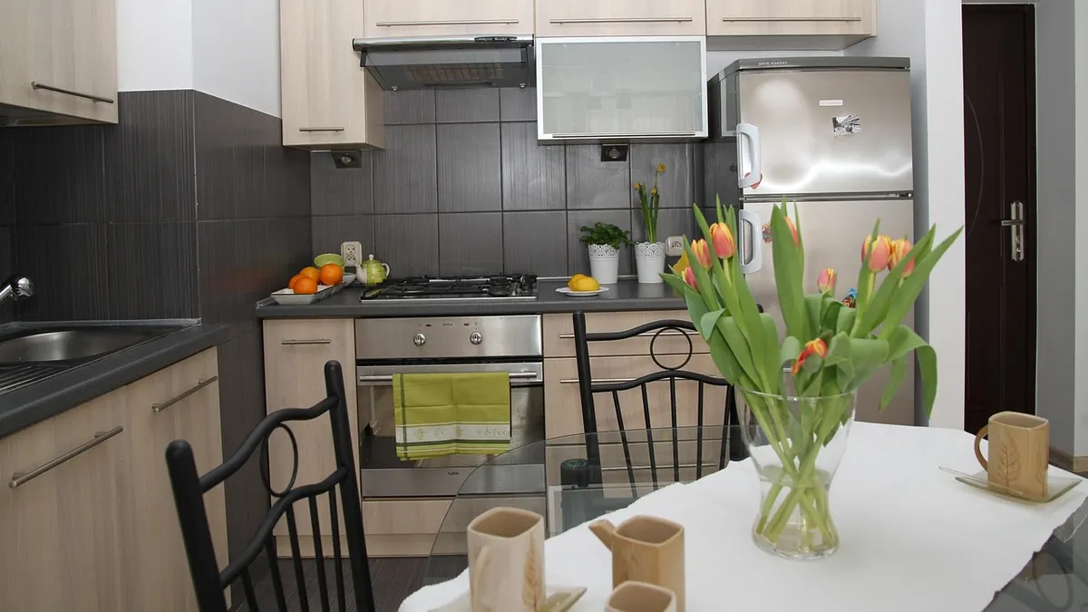 Cozinha com geladeira inox, fogão e mesa com tulipas